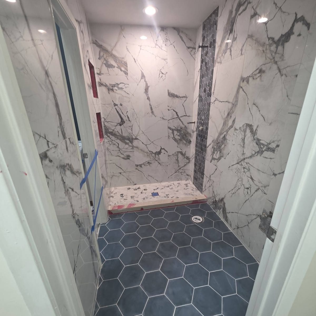 Marble-look tile shower with hexagon floor tile