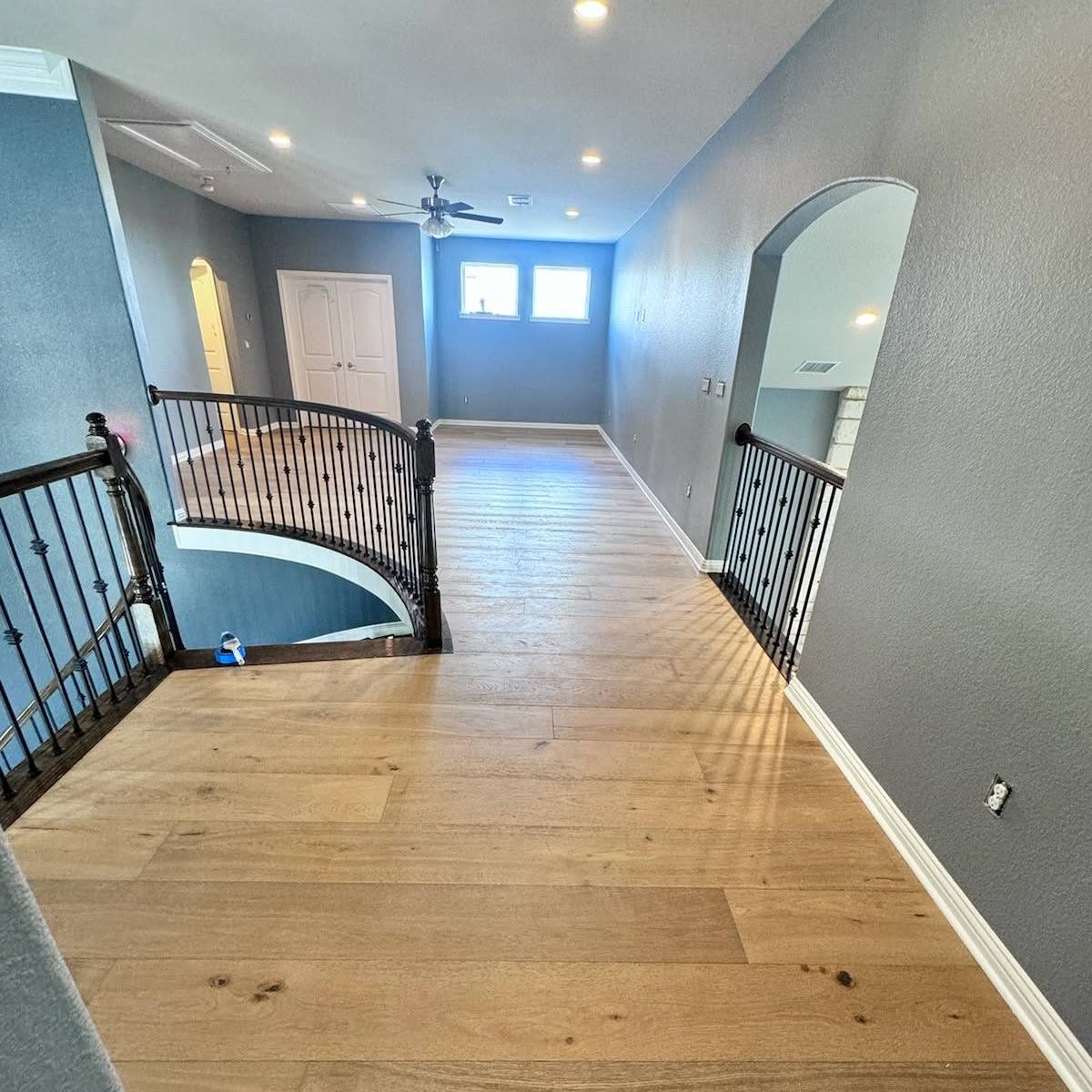 Stair landing with curved iron railing and new hardwood flooring